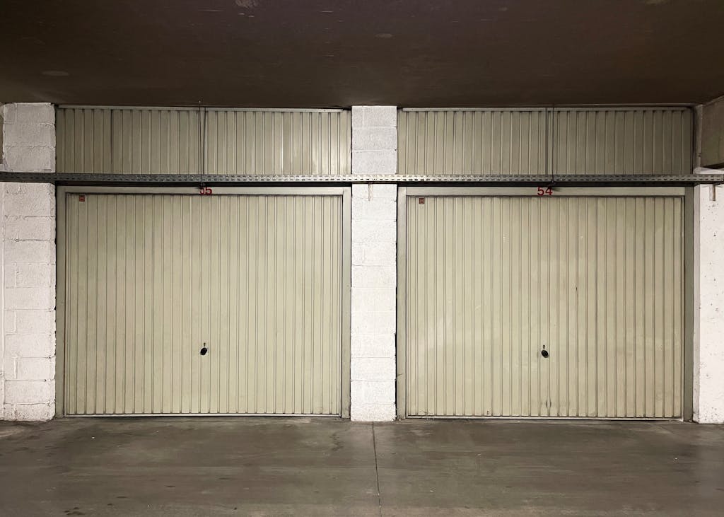 Two closed garage doors inside an empty warehouse space.